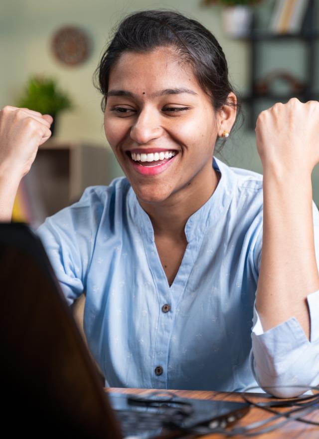 Indian woman celebrating at laptop