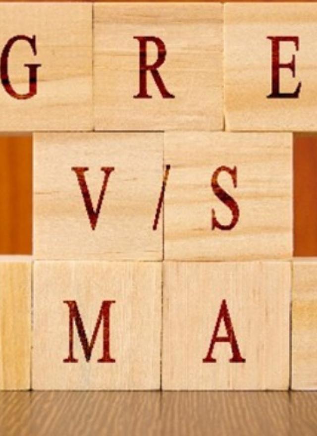 wooden letter blocks stacked on top of each other, spelling out GRE and GMAT