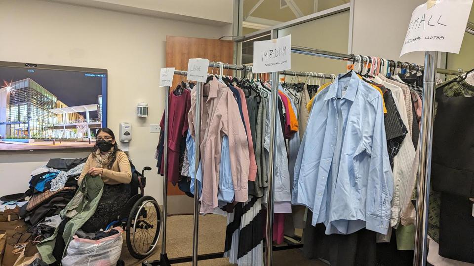 Gloria Navarro holding clothes in conference room in Gallagher Hall