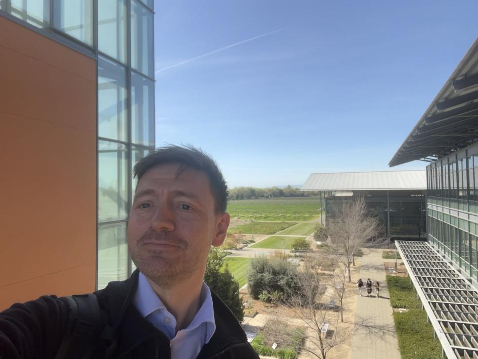 Tue Rasmussen taking a selfie on a balcony with UC Davis campus in the background